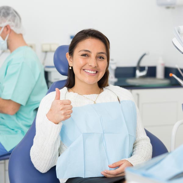 person with thumb up at dentist